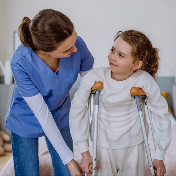 child using crutches with doctor